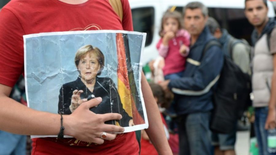 MIGRATION 1178158-une-refugiee-tient-un-portrait-de-la-chanceliere-allemande-angela-merkel-le-5-septembre-2015-a-munic