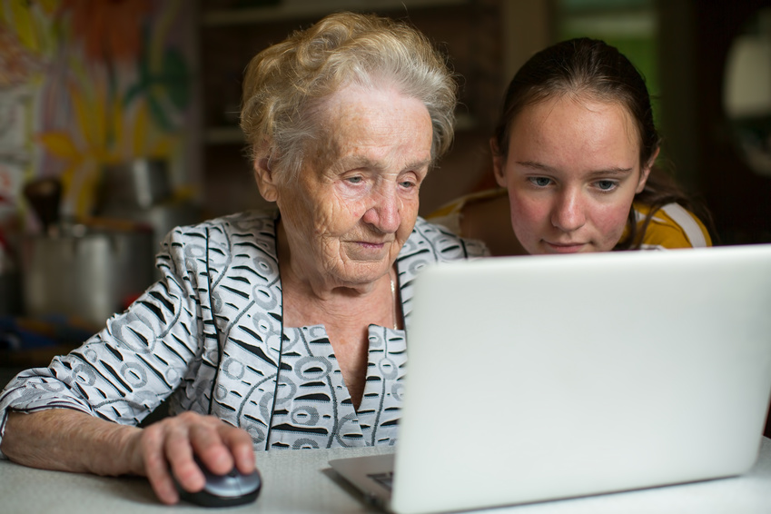 Elderly woman with her granddaughter working on laptop.